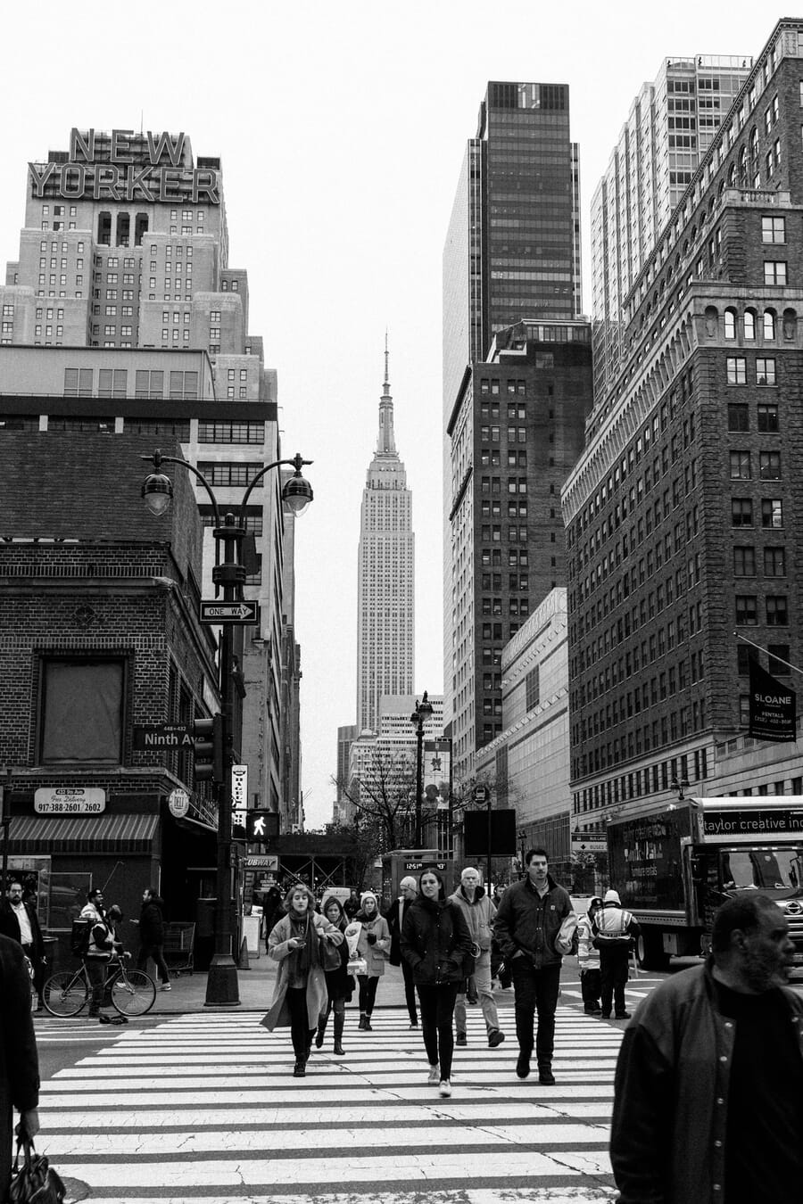 Pedestrians crossing a busy crosswalk near the Empire State Building — urban photography capturing the energy of city life