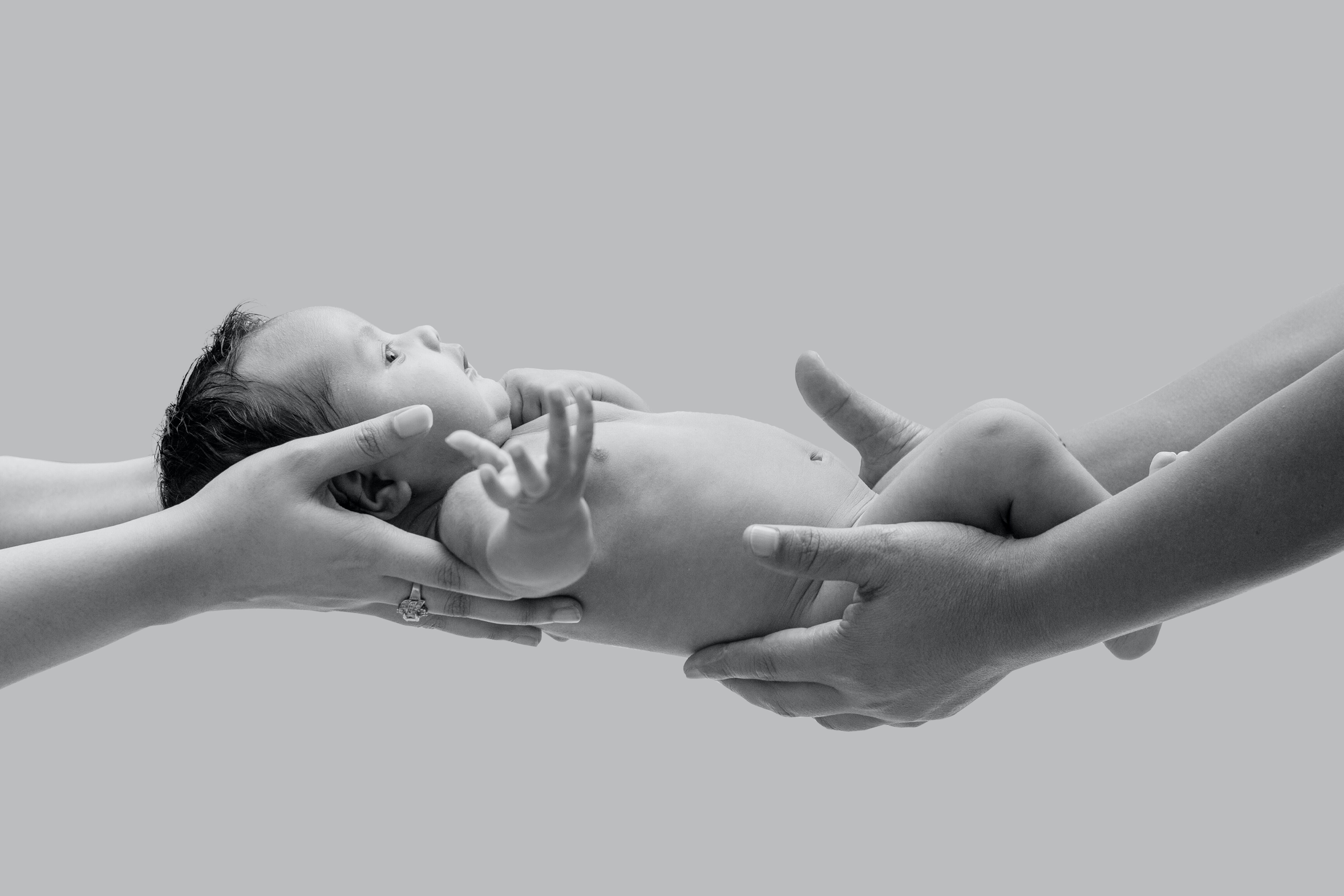 Two sets of hands holding a baby