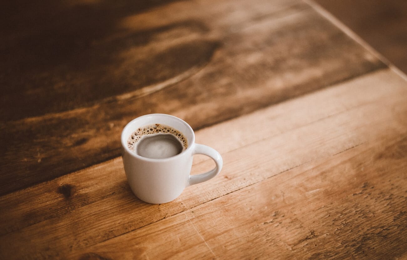 Cafe lifestyle shot of a single coffee mug on a wooden table in warm morning light
