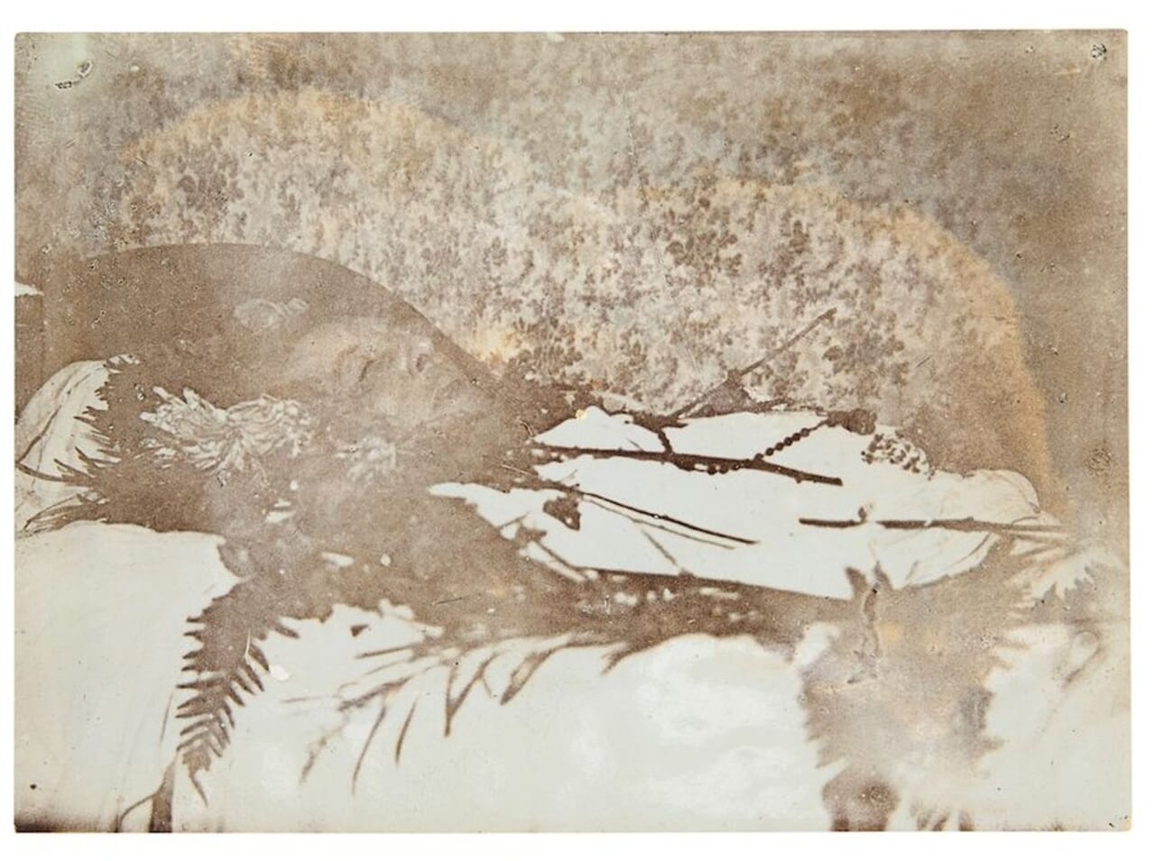 The aged, faded 1900 photograph of Oscar Wilde laid out on his deathbed among flowers, taken by Maurice Gilbert.