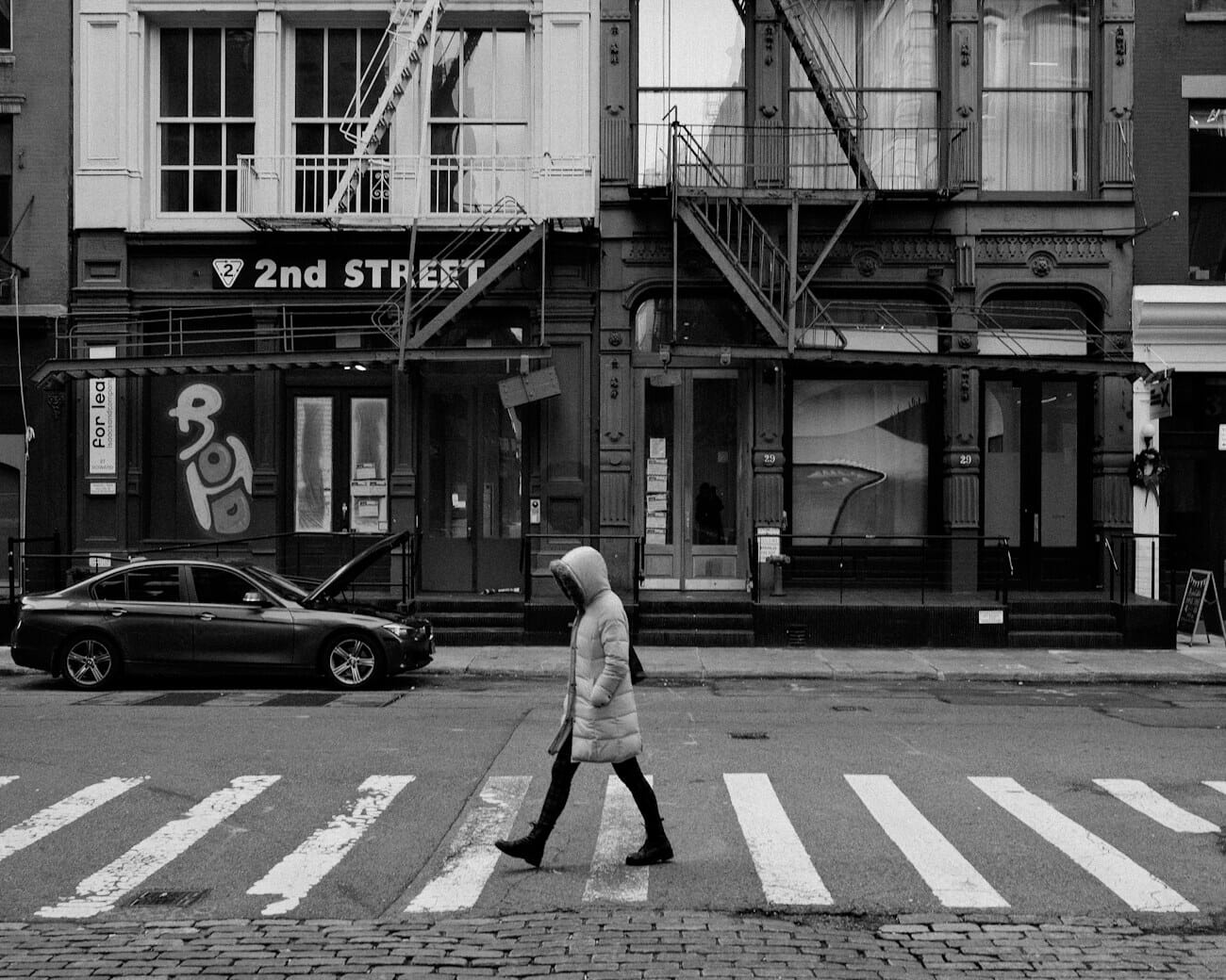 A pedestrian crossing a city street, the kind of candid scene a 26mm prime is built for