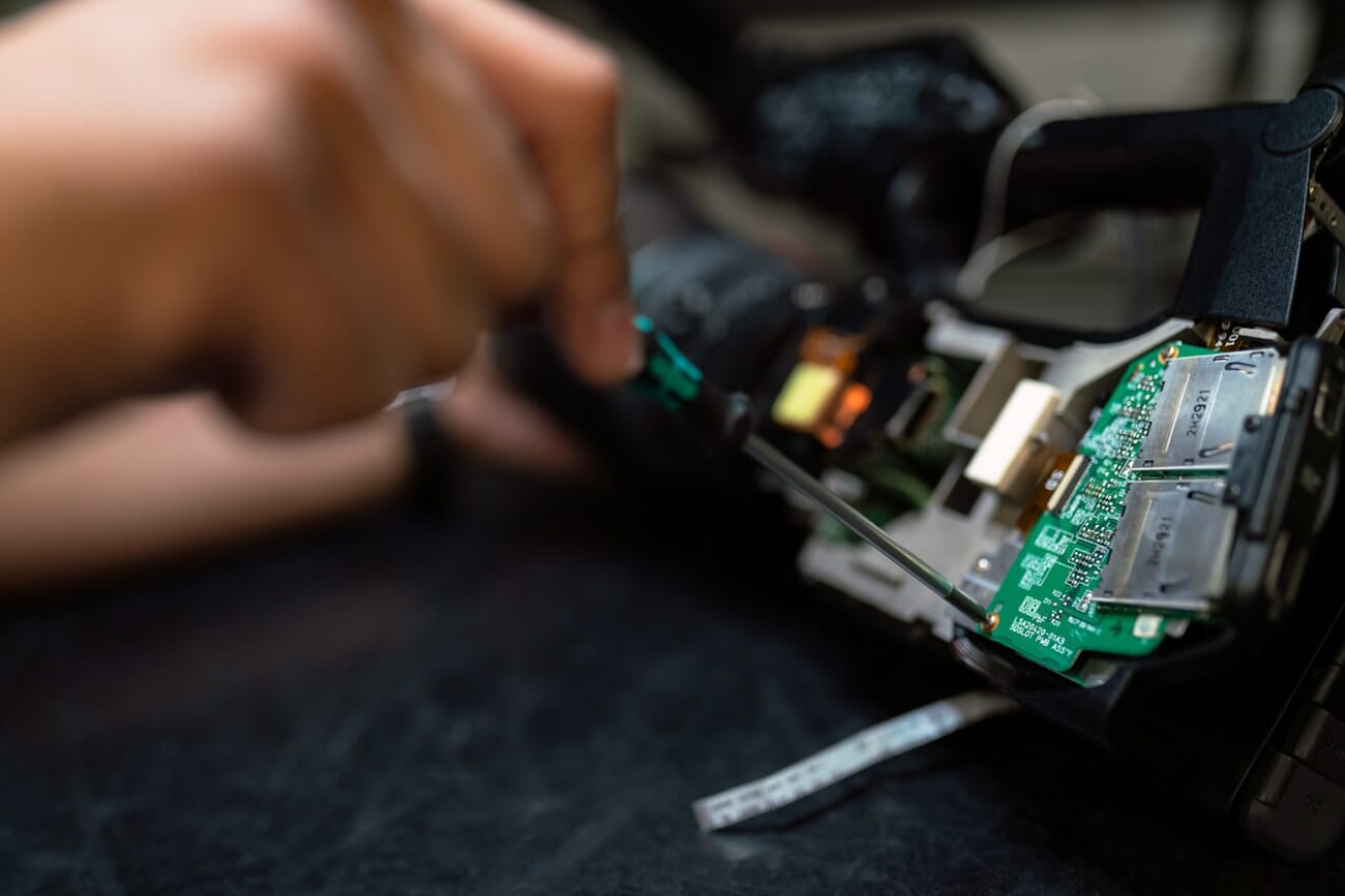 A technician working on camera electronics at a service bench