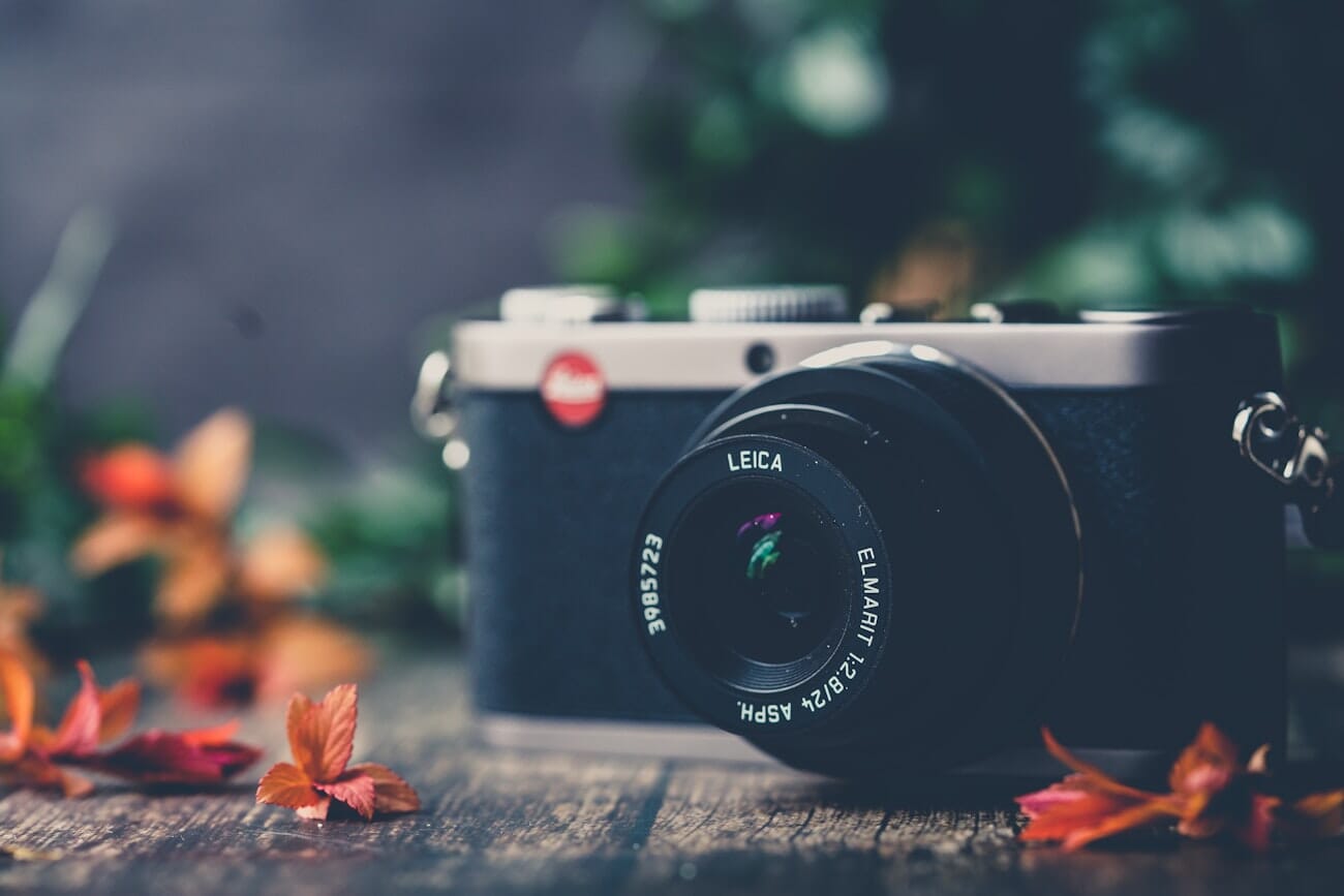 Leica camera showing its red dot logo on a wooden table