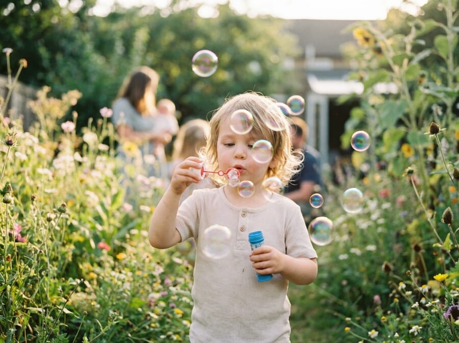 Child blowing bubbles in garden