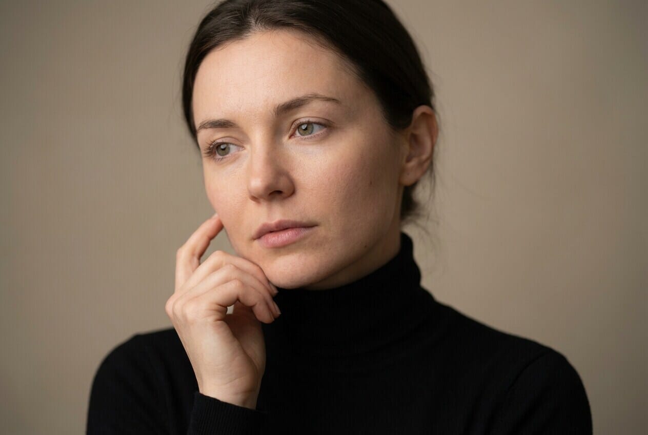 Woman gently touching cheek with thoughtful expression