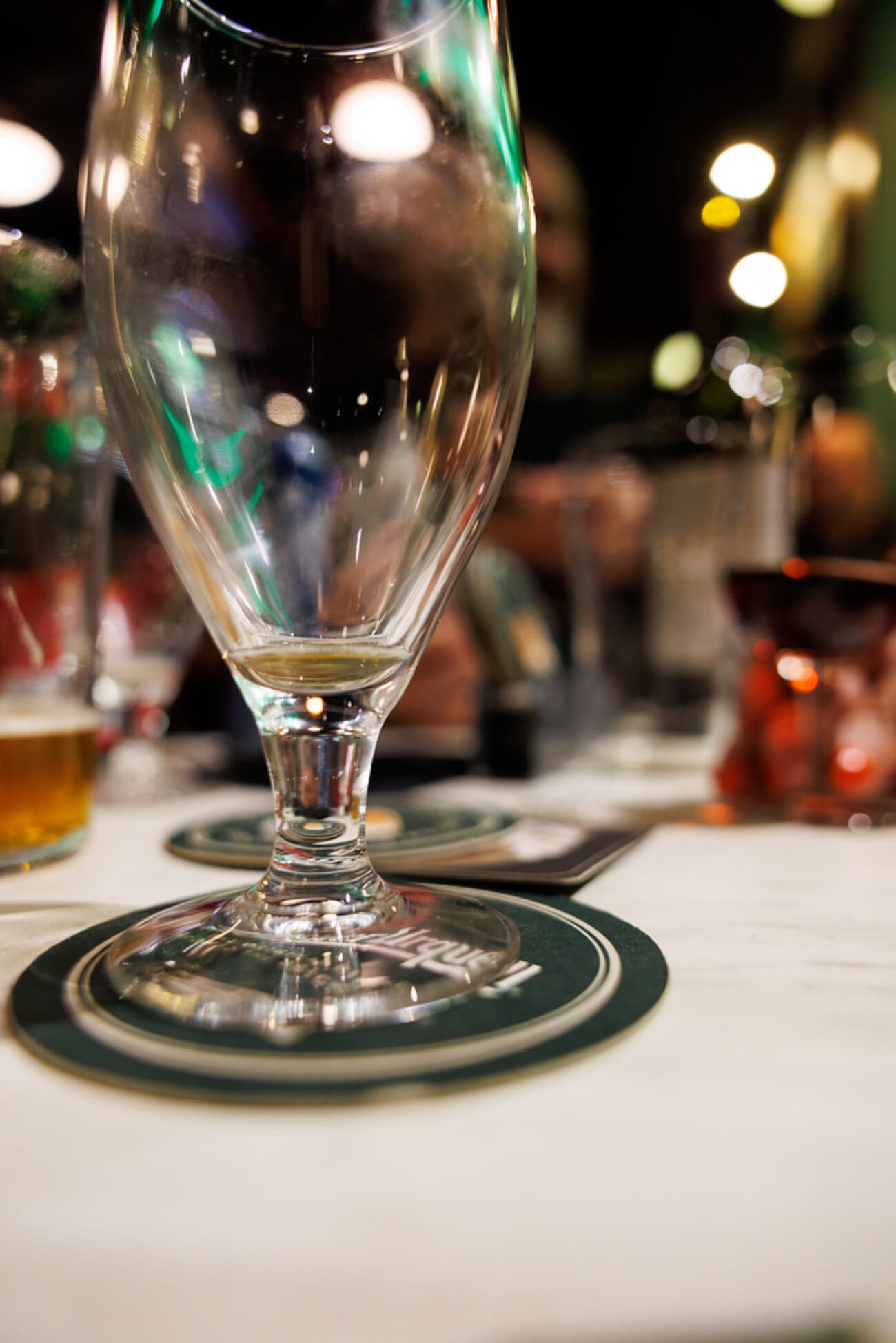 Close-up of a beer glass with beautiful bokeh lights in the background, shot with Canon RF 24-70mm f/2.8L at 24mm, 1/60s, ISO 1250