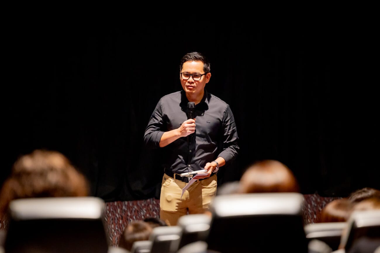 Speaker isolated against dark background with shallow depth of field, shot with Canon RF 70-200mm f/2.8L IS USM at 200mm, 1/40s, ISO 2500