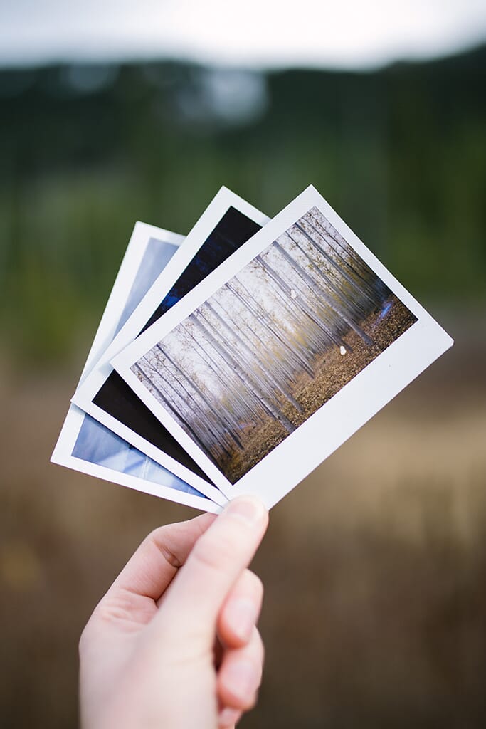 person holding several photo prints