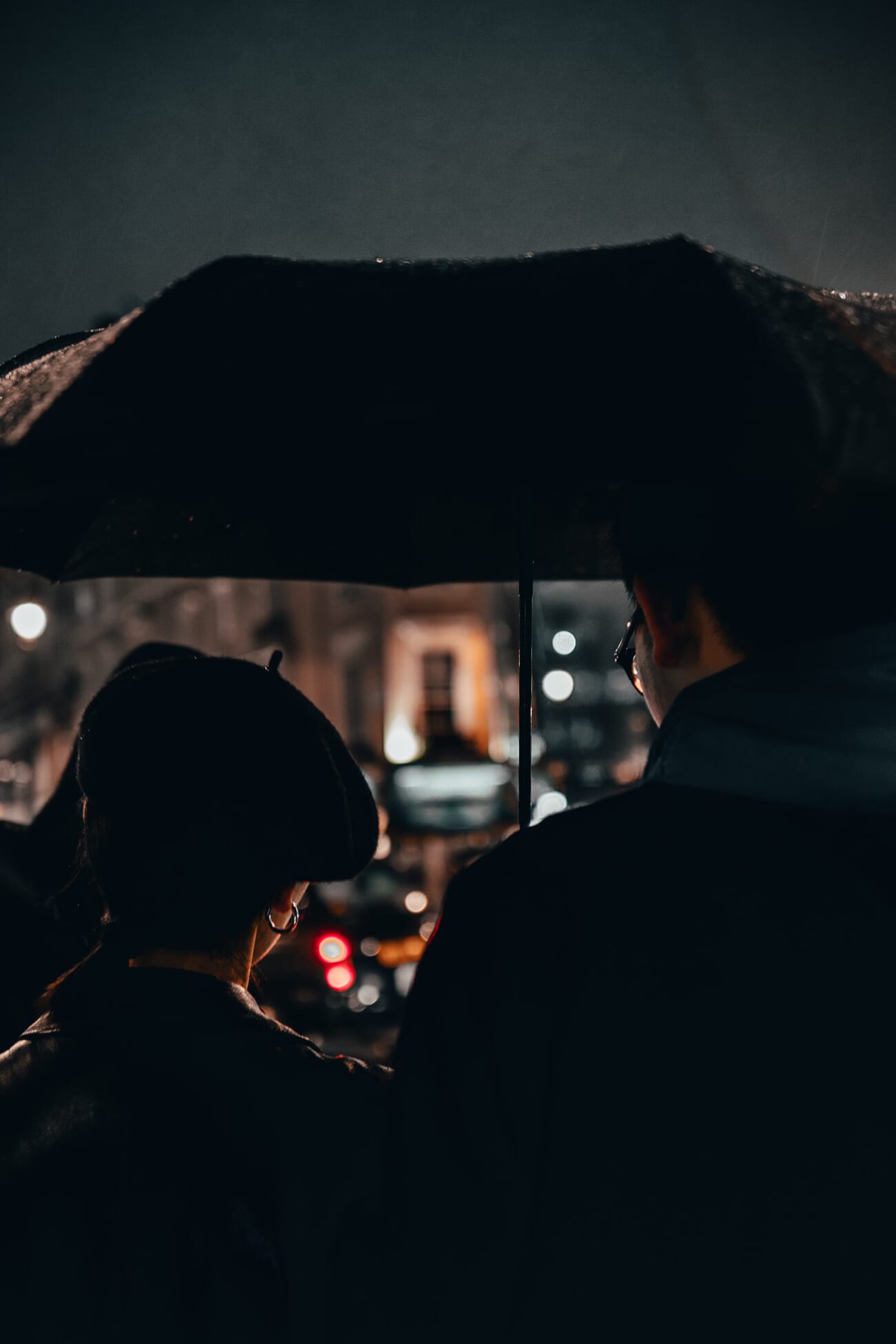 People under umbrella at night on a reflective wet street