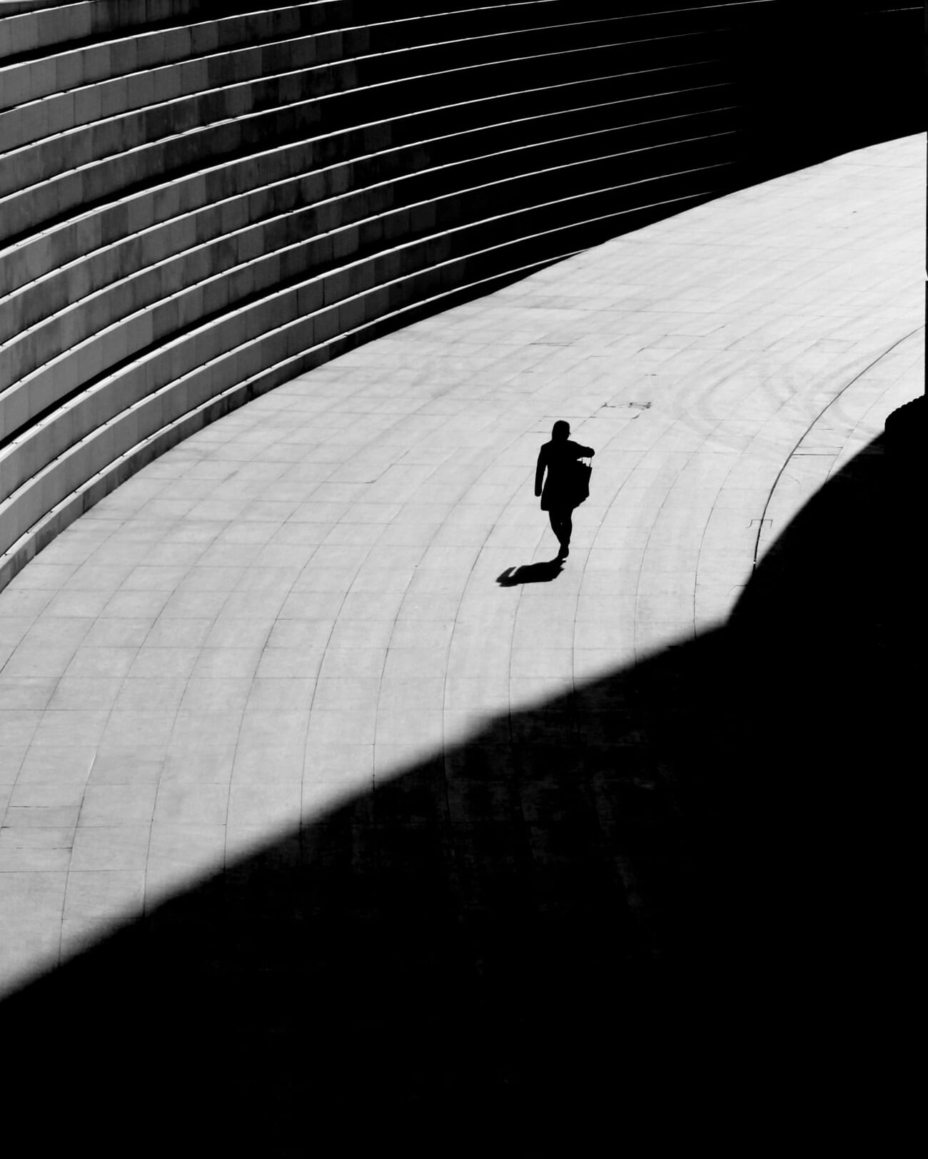 Person walking with strong midday shadow converted to moody black and white