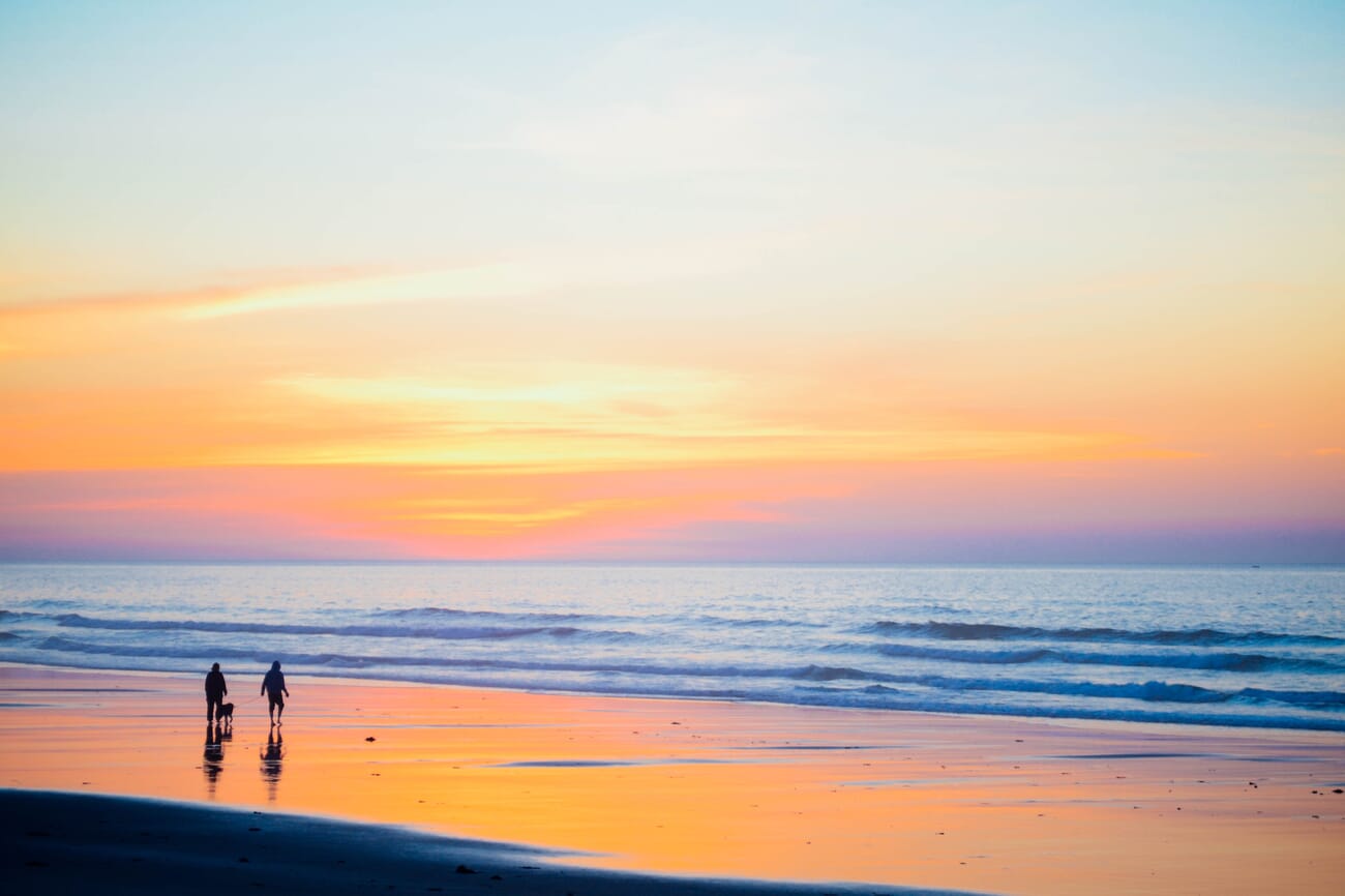 Walkers on a beach during golden hour with warm directional light