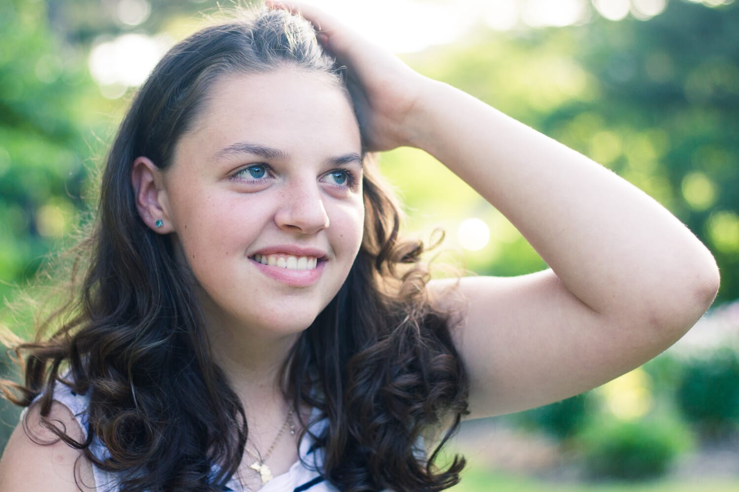 Headshot of a girl with blue eyes running a hand through her long hair.