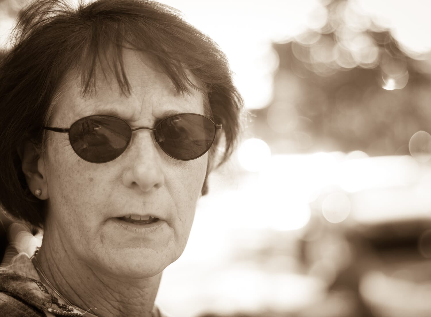 Woman looking directly at the viewer in monochrome with background bokeh.