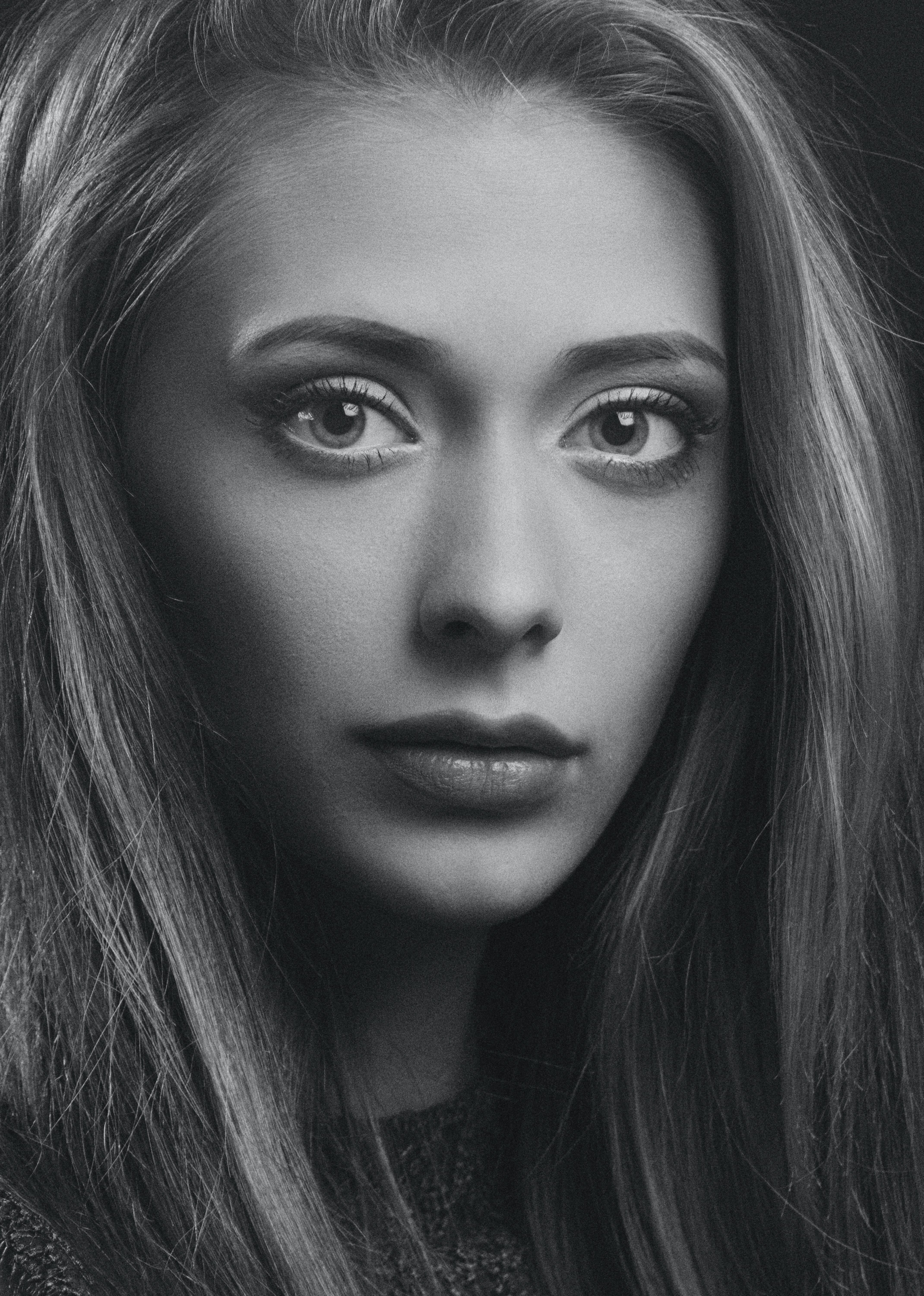 High-contrast black and white portrait featuring a model with striking eyes and flowing hair. The image highlights the effects of lighting in photography and external flash.