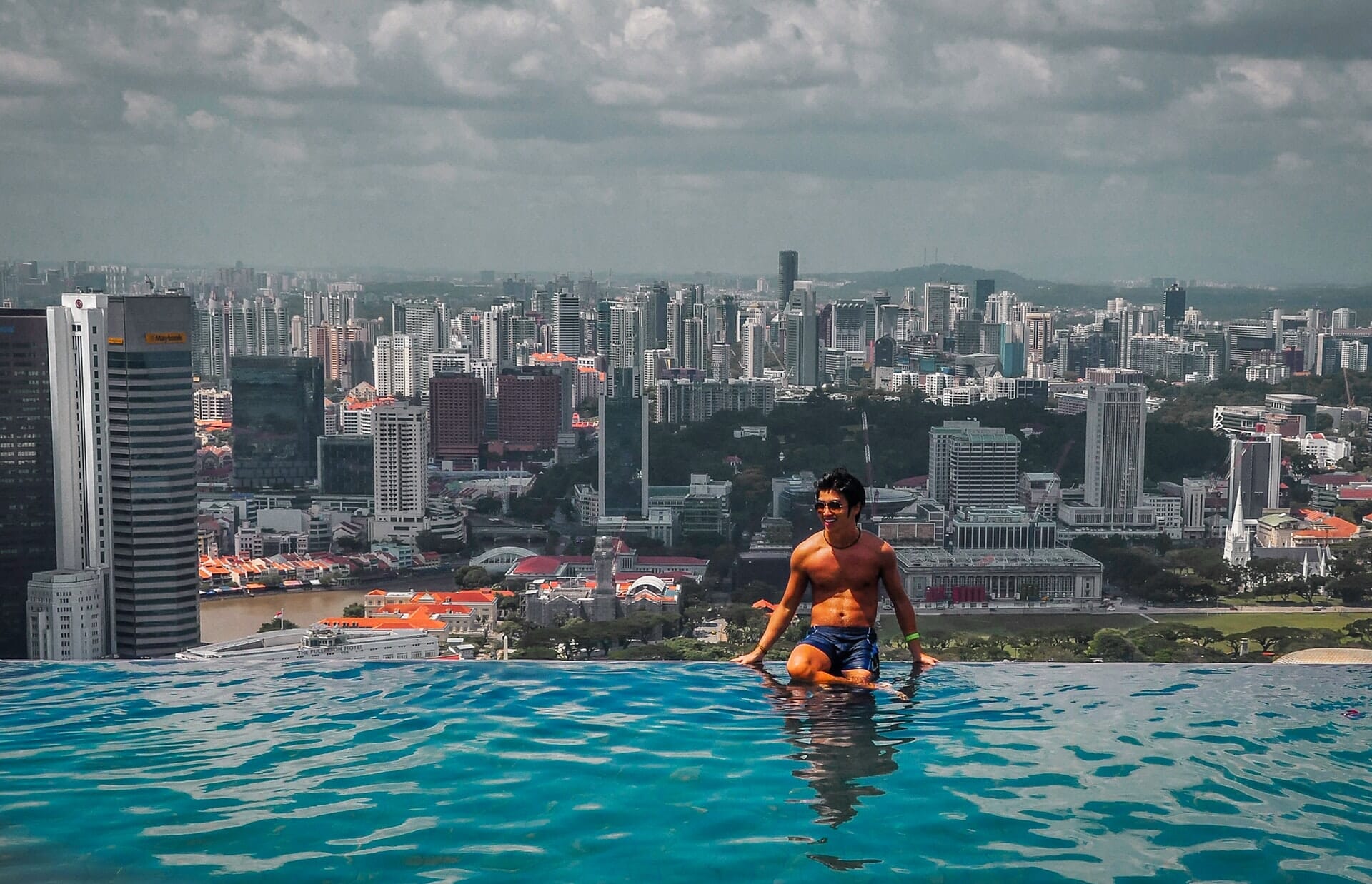 Model sitting on ledge of infinity pool at Marina Bay Sands, Singapore