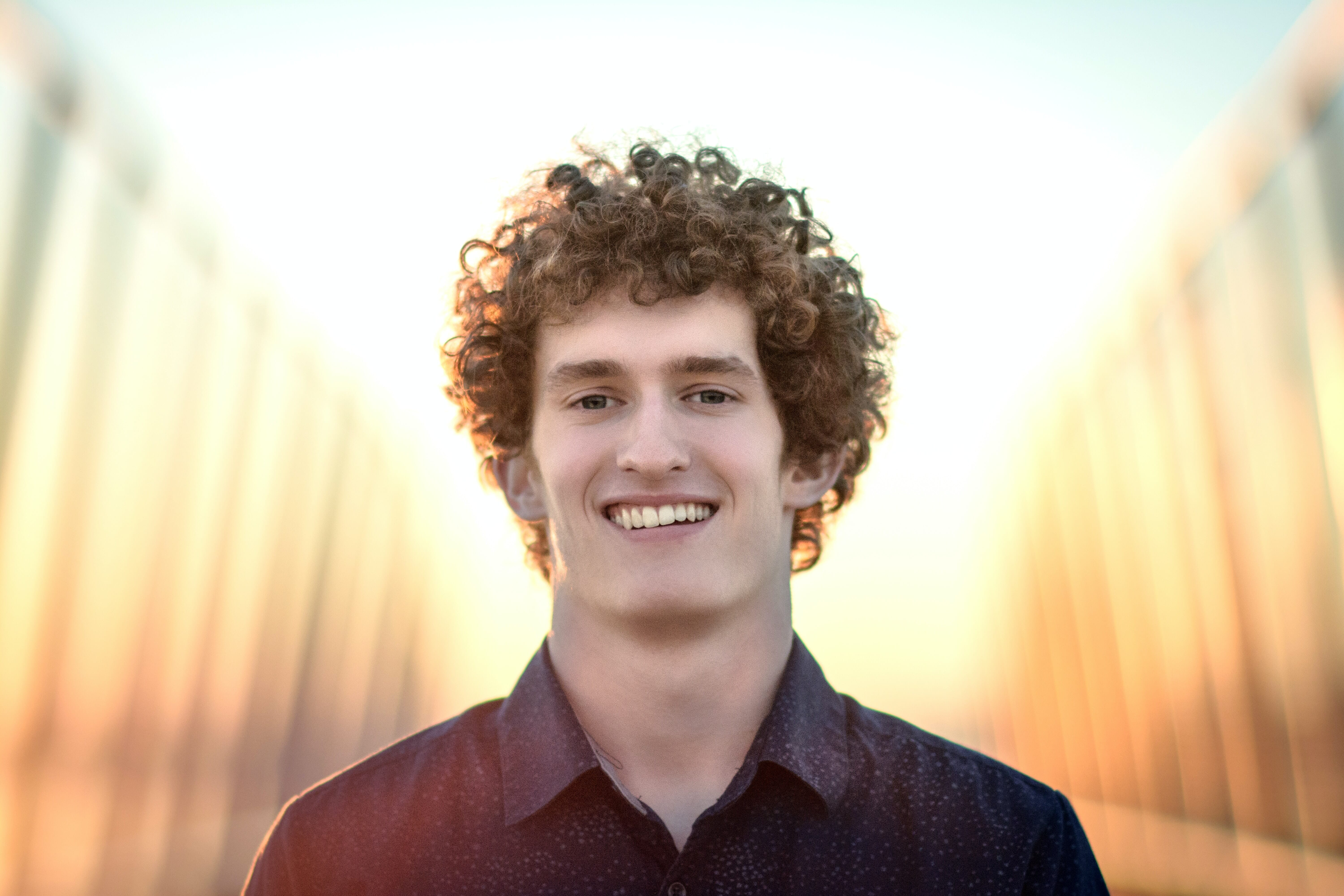Capture stunning portraits with a pure white backdrop! This image features a smiling individual with curly hair, showcasing vibrant lighting for a striking and clean aesthetic. Perfect for your photography.