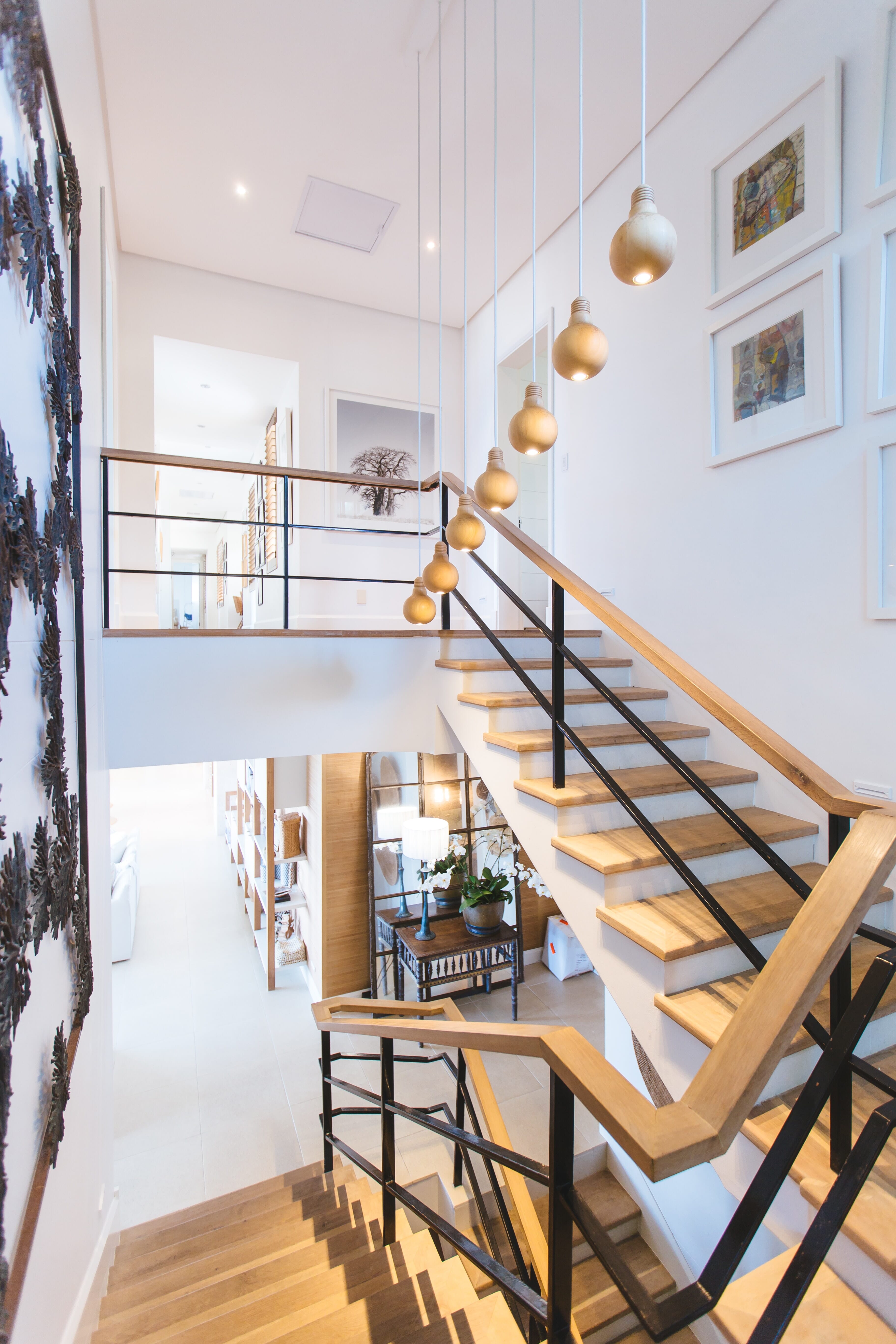 Interior of a home with a light wooden staircase and hanging lights.
