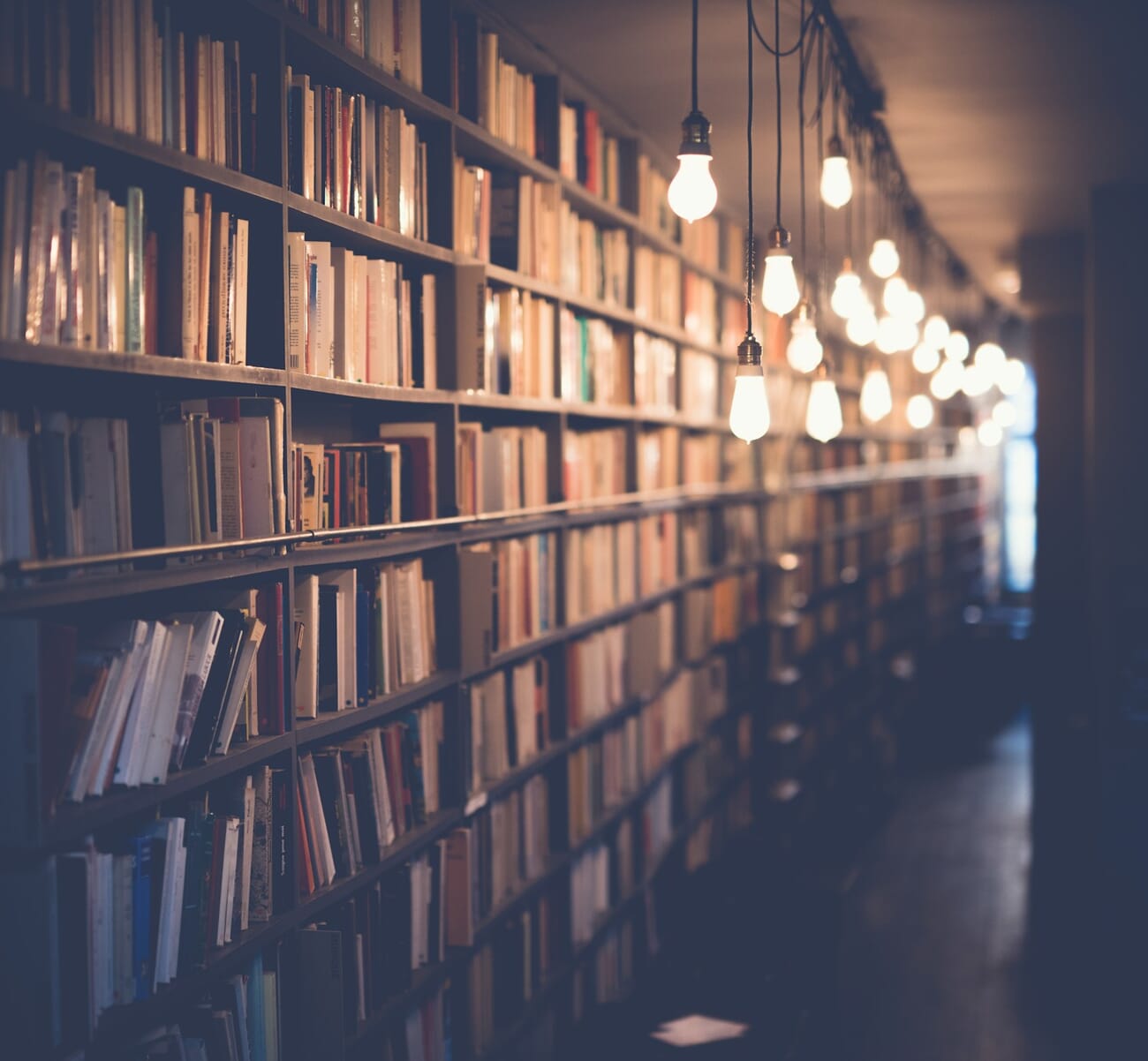 Dim library aisle lit by hanging bulbs, shot handheld at f/1.6