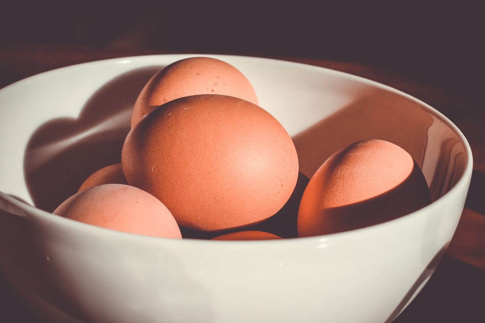 Close-up image of brown eggs in a white bowl