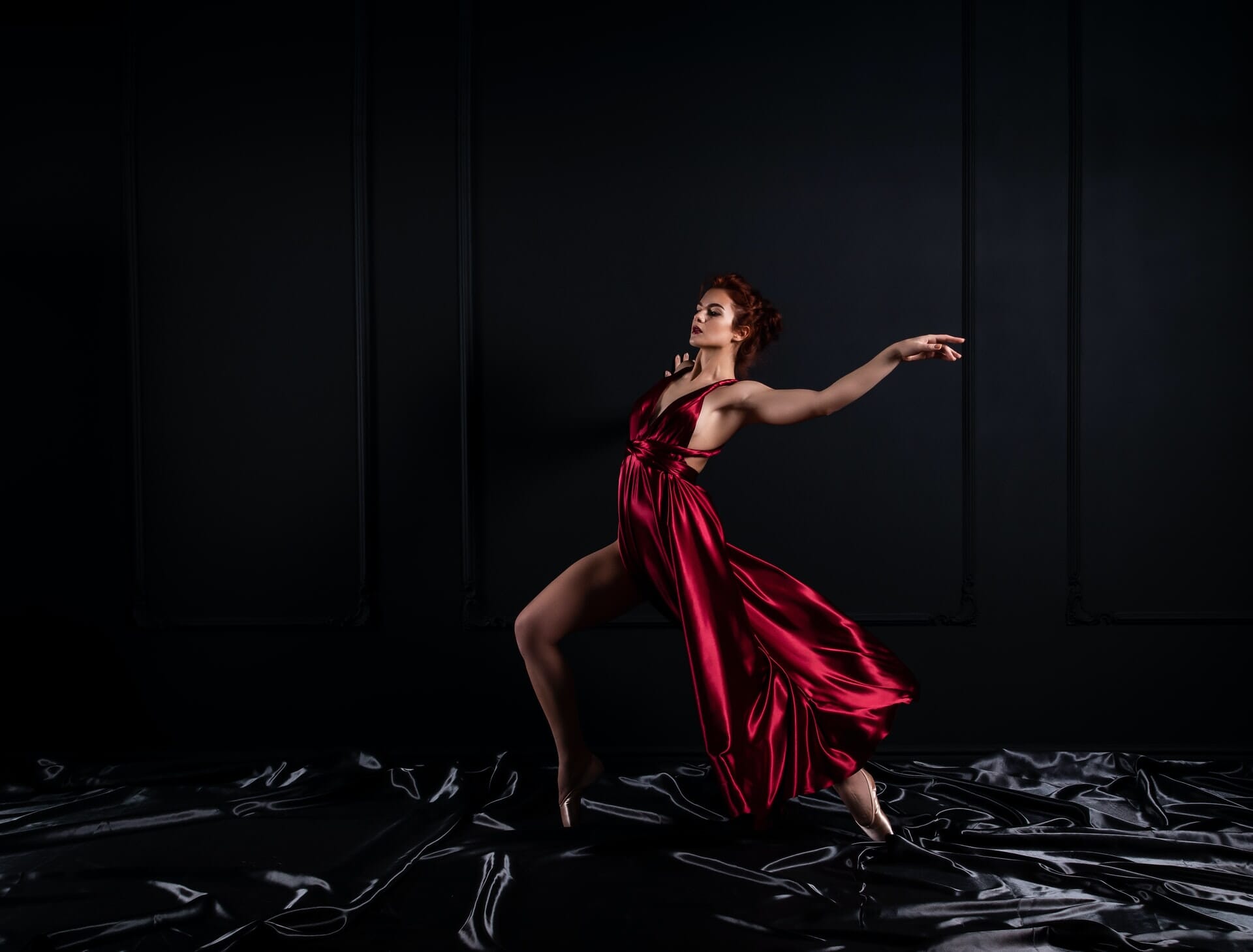 Woman in shiny red gown dancing.