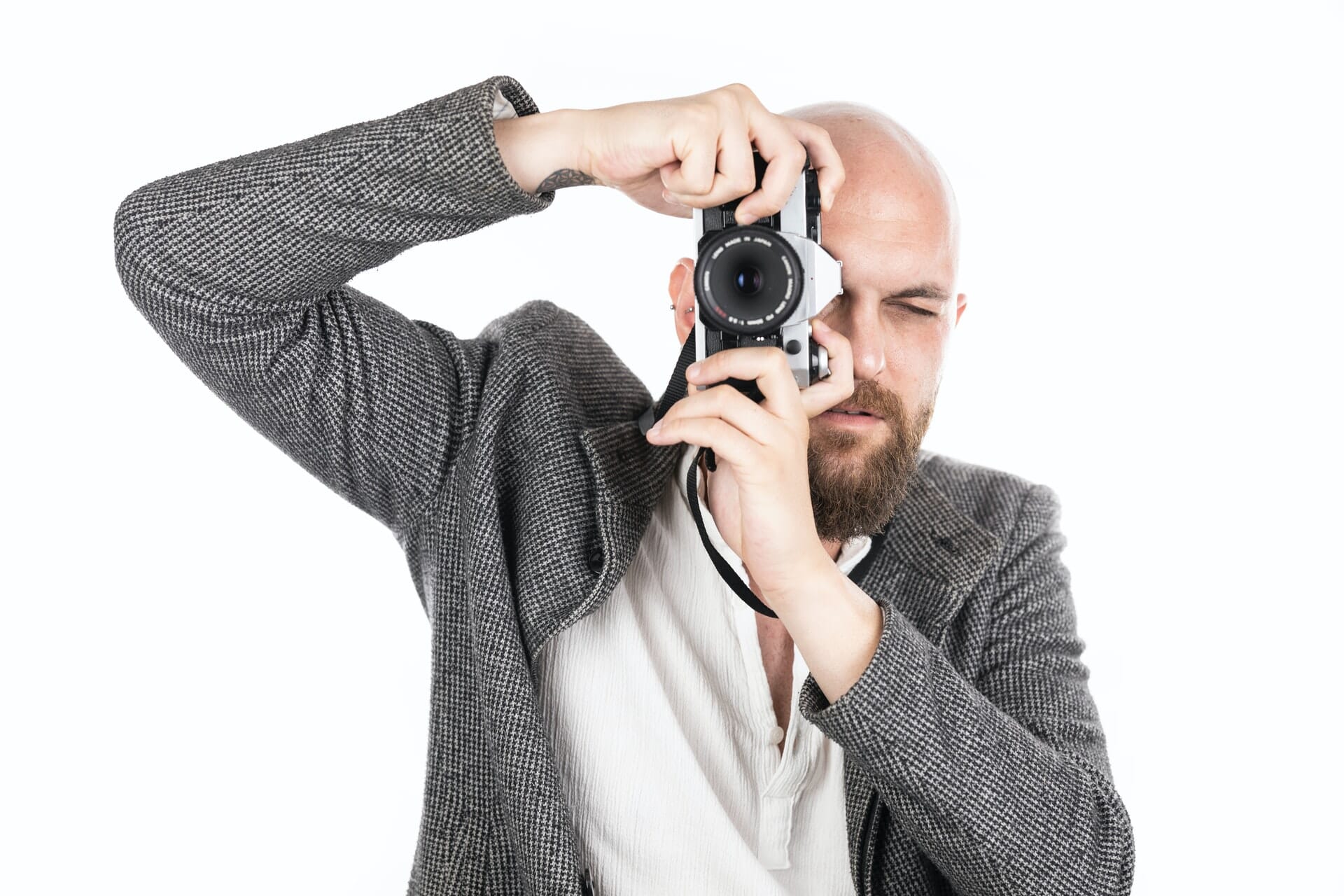 Man holding a camera up to his eye, taking a photograph.