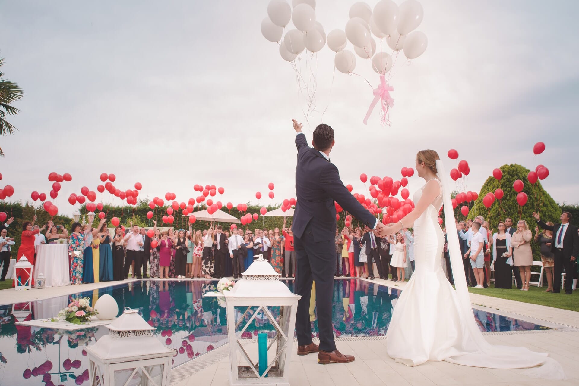 Bride and groom releasing a bunch of balloons outdoors.