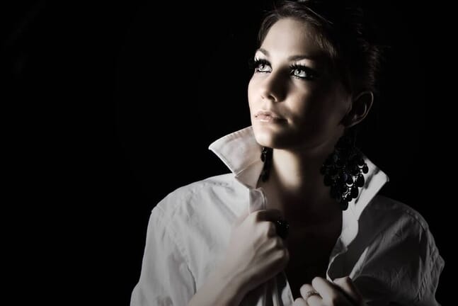 Woman in dark with light shining on her face.