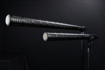 Closeup of two sleek shotgun mics against a black background