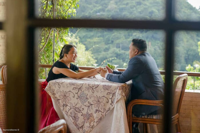 Picture taken from the inside of a couple outside sitting down and holding hands