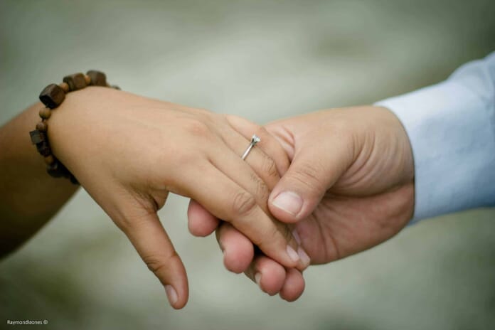 close-up picture of two hands holding each other with a visible engagement ring