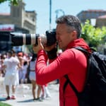 Photographer in red shirt with backpack taking pictures on a busy street