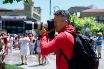 Photographer in red shirt with backpack taking pictures on a busy street