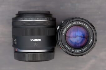 Close-up of a Canon 35mm lens and a Canon 50mm lens sitting on a table.