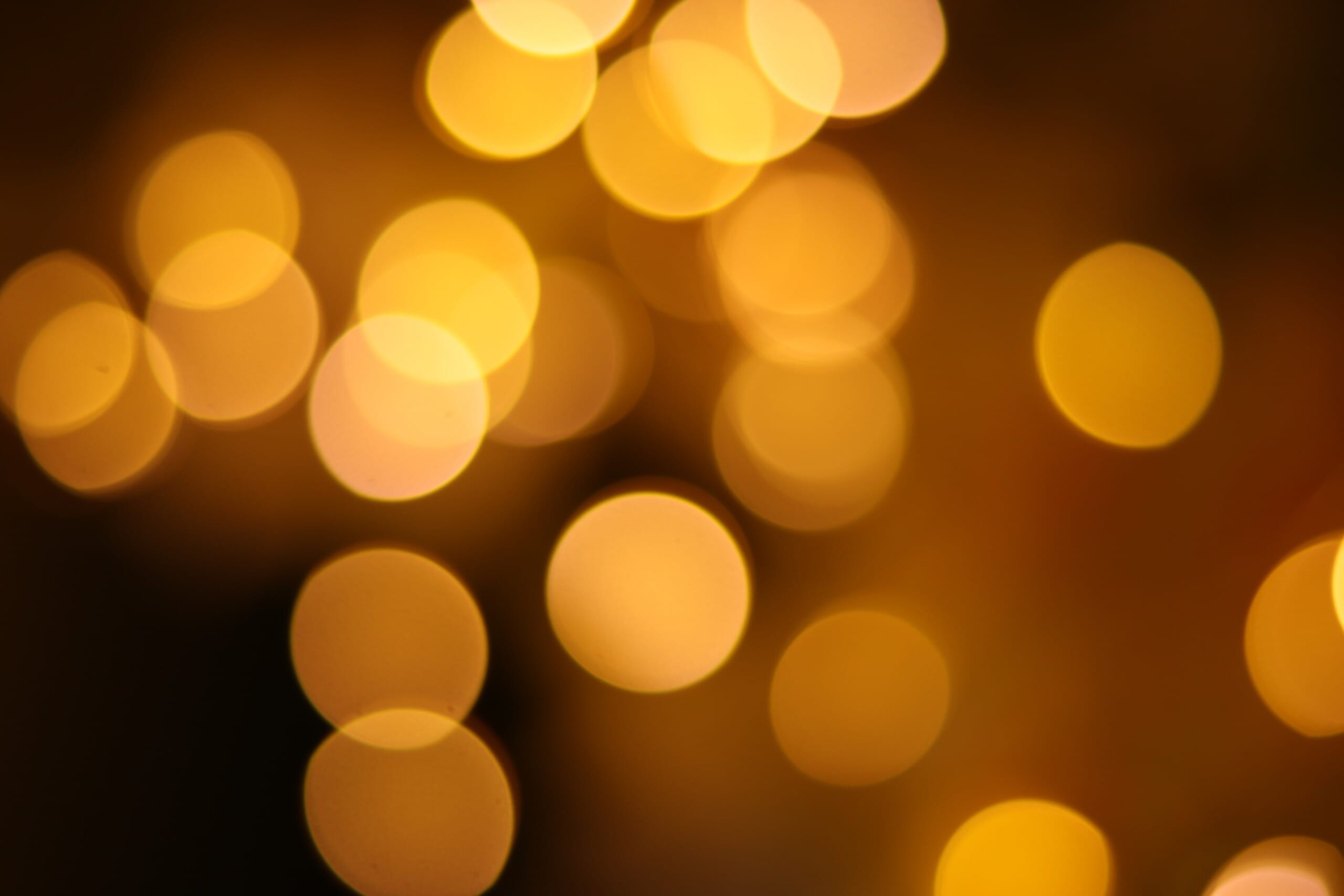 Capturing bokeh example of a cluster of yellow lights surrounded by darkness.