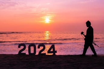 2024 signs on the beach with a photographer in the background, sunset.