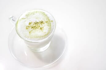 Hot matcha Japanese milk green tea latte on white table. high key photography.