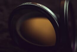 Close-up of two camera filters in dim lighting on a black background.