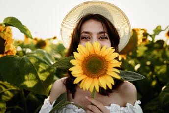 Portrait of a woman with a sunflower in a sunflower field.