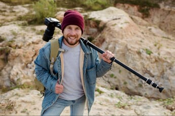 Man carrying a monopod mounted with a camera.