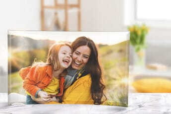 A glass photo print on a marble counter depicting a mother and daughter laughing together at sunset.