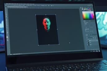 Black laptop with Photoshop open and displaying a red and green portrait.