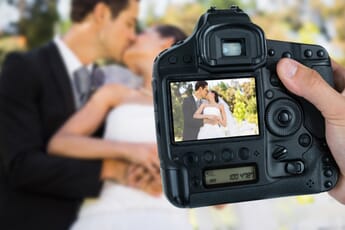 View of camera taking a photo of a newly wed couple.