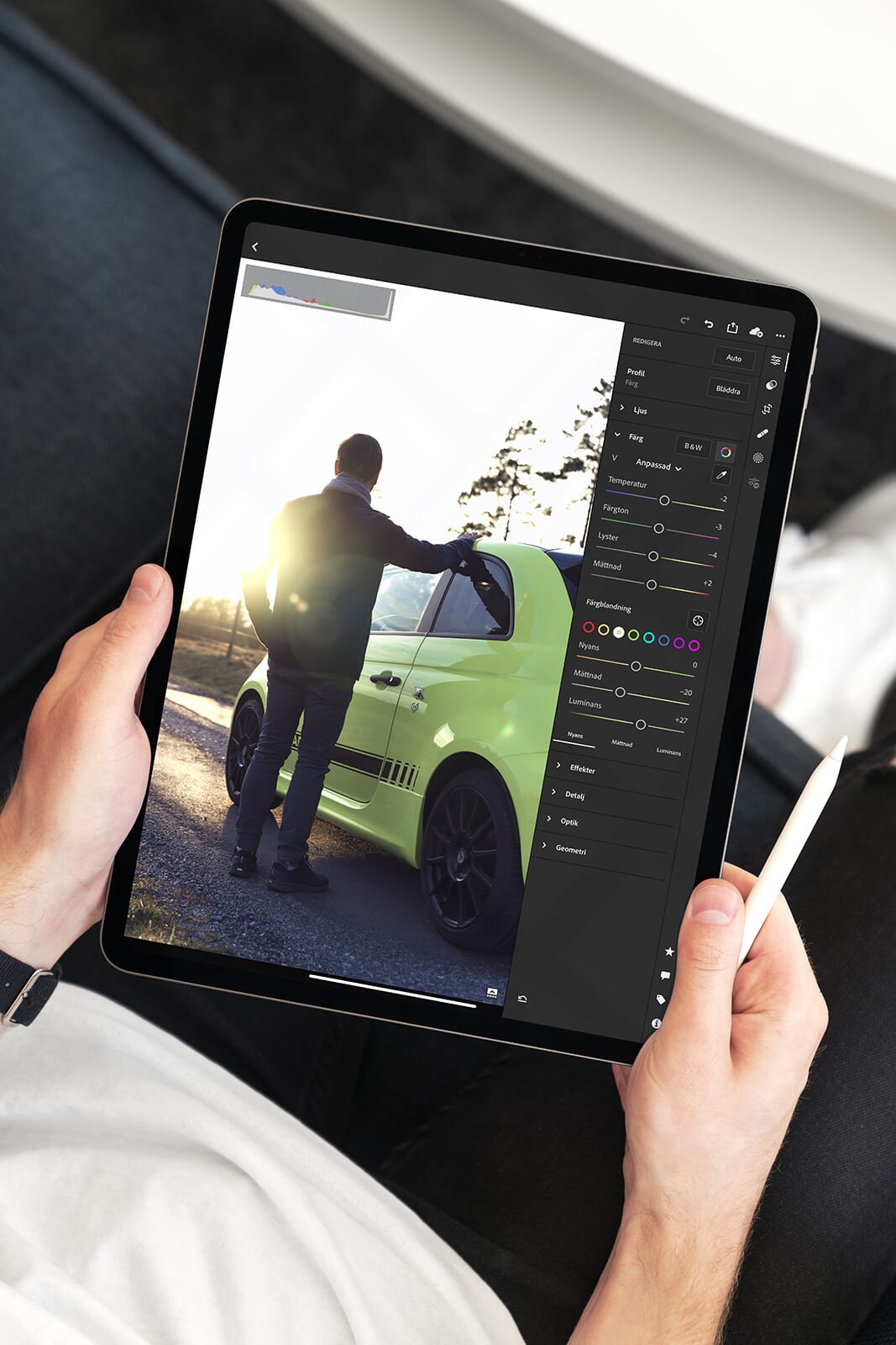 Tablet with photo editing software open featuring a photo of a man standing next to a green sports car at sunset.
