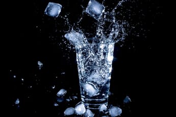 ice splashing in a glass of water