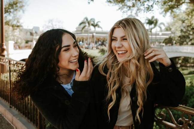 Two female friends laughing outdoors.