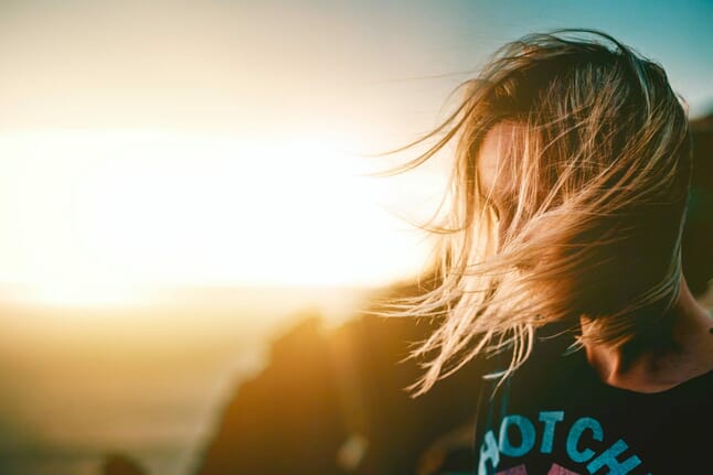 woman blowing hair with sun in the background