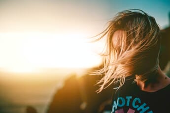 woman blowing hair with sun in the background