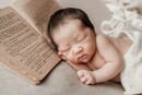 Baby sleeping with a book photo prop.
