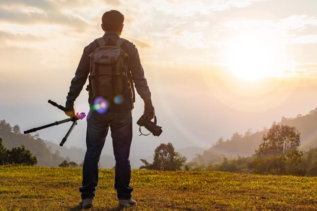 Man holding a tripod and a camera.