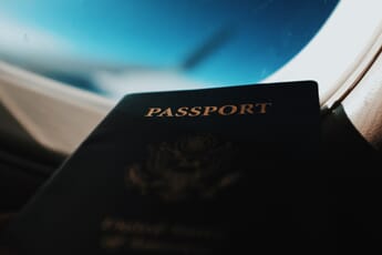 Close-up of passport with gold lettering in front of a plane window